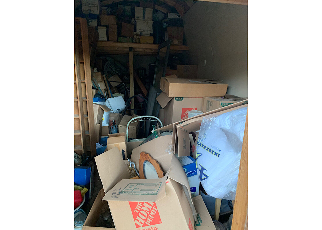 Dallas Shed Junk Removal A dark, cluttered storage shed in Dallas filled with various Home Depot moving boxes, furniture, and household debris ready for junk removal